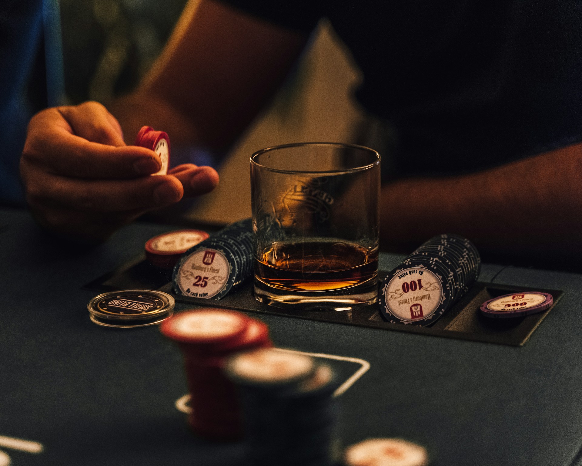whiskys pohár és zsetonok egy férfi kézben
