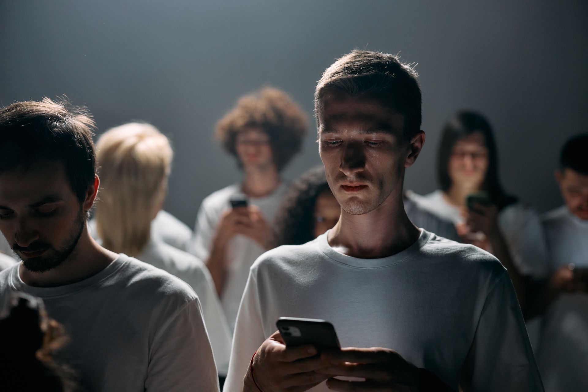 sok ember egy sötét teremben, mindenki a telefonját nézi a monitor világítja meg az arcukat