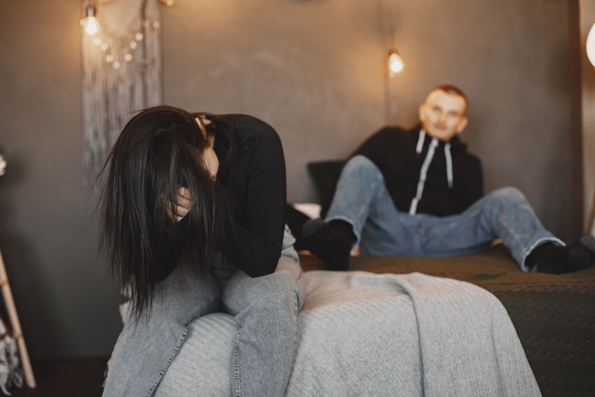 férfi ül az ágyon, a nő a kezeibe temeti az arcát