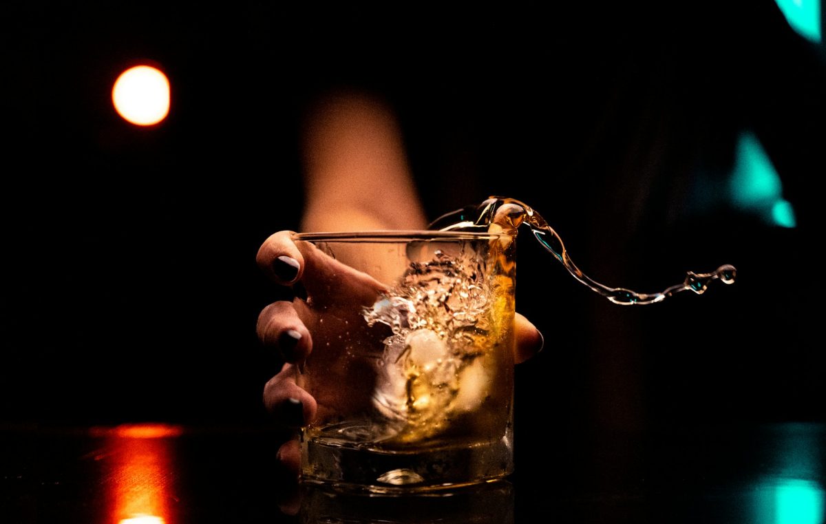 sötét háttér előtt pohárból kiloccsan az alkohol